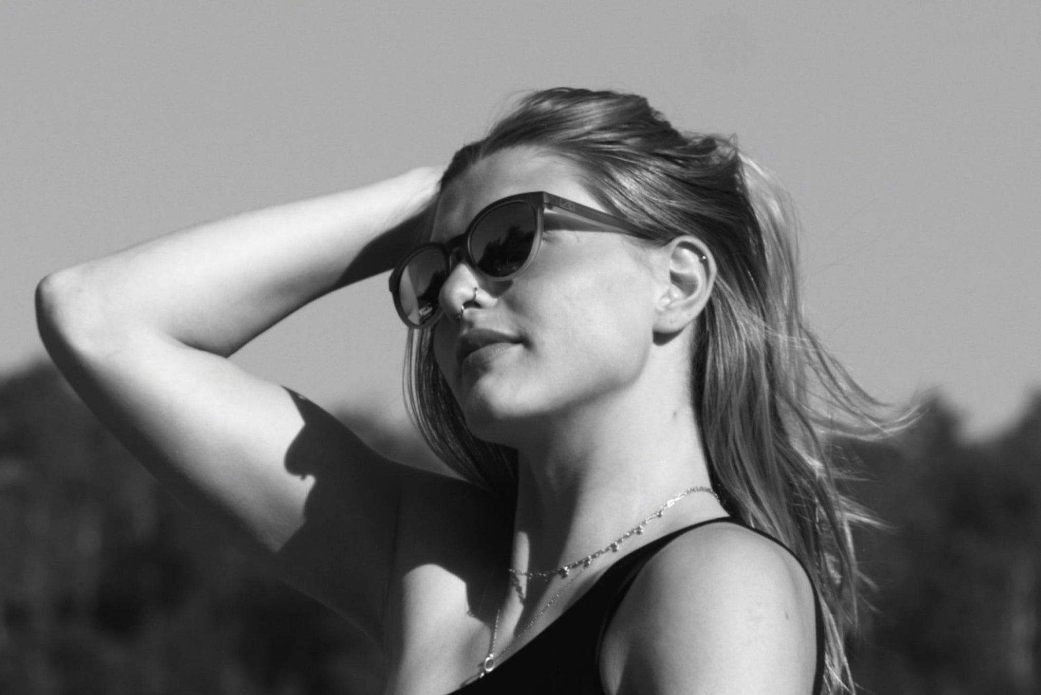  Woman in a black bikini top standing outdoors with trees in the background
